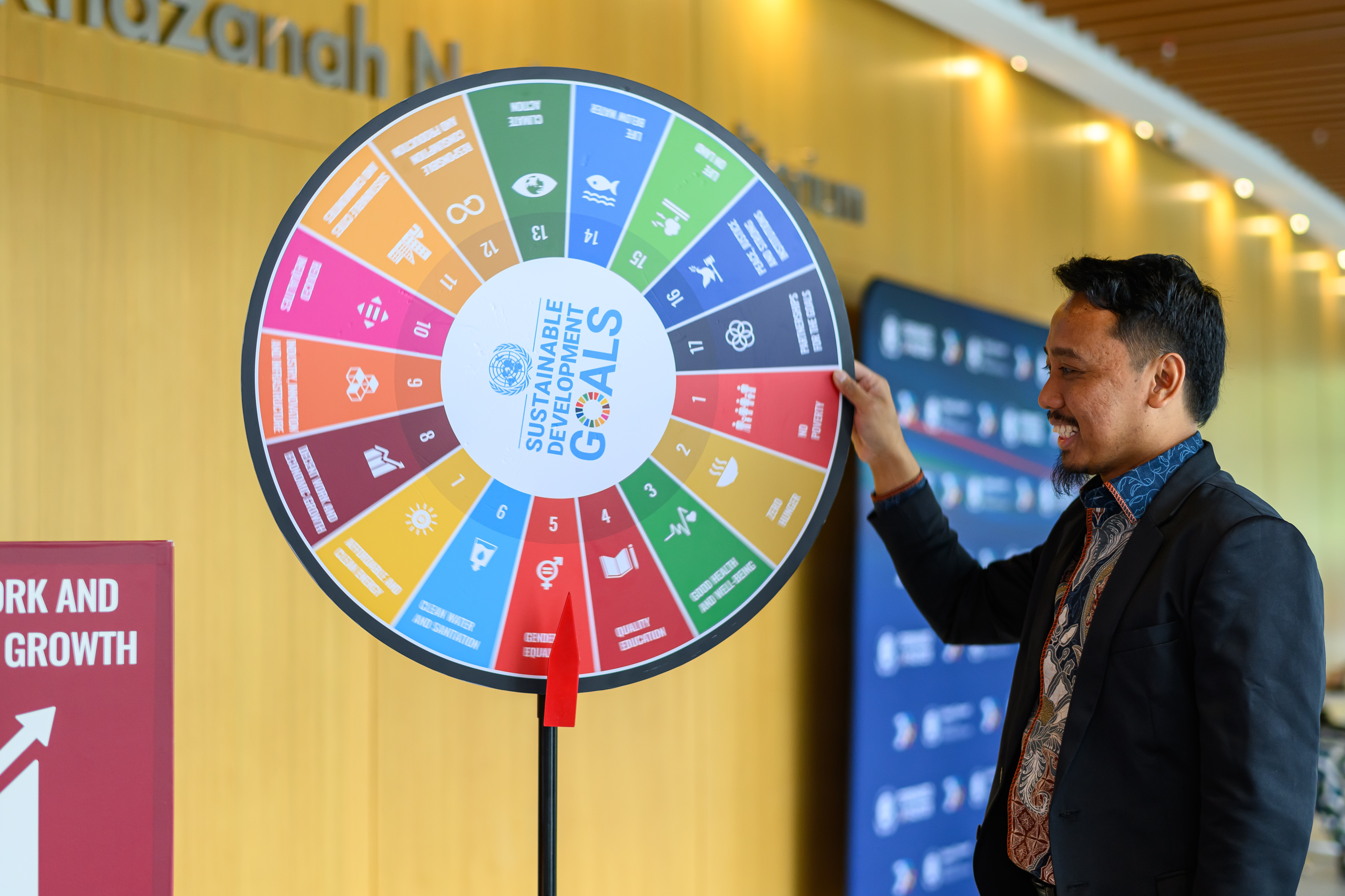 man spinning a colorful wheel with the 17 SDGs represented 