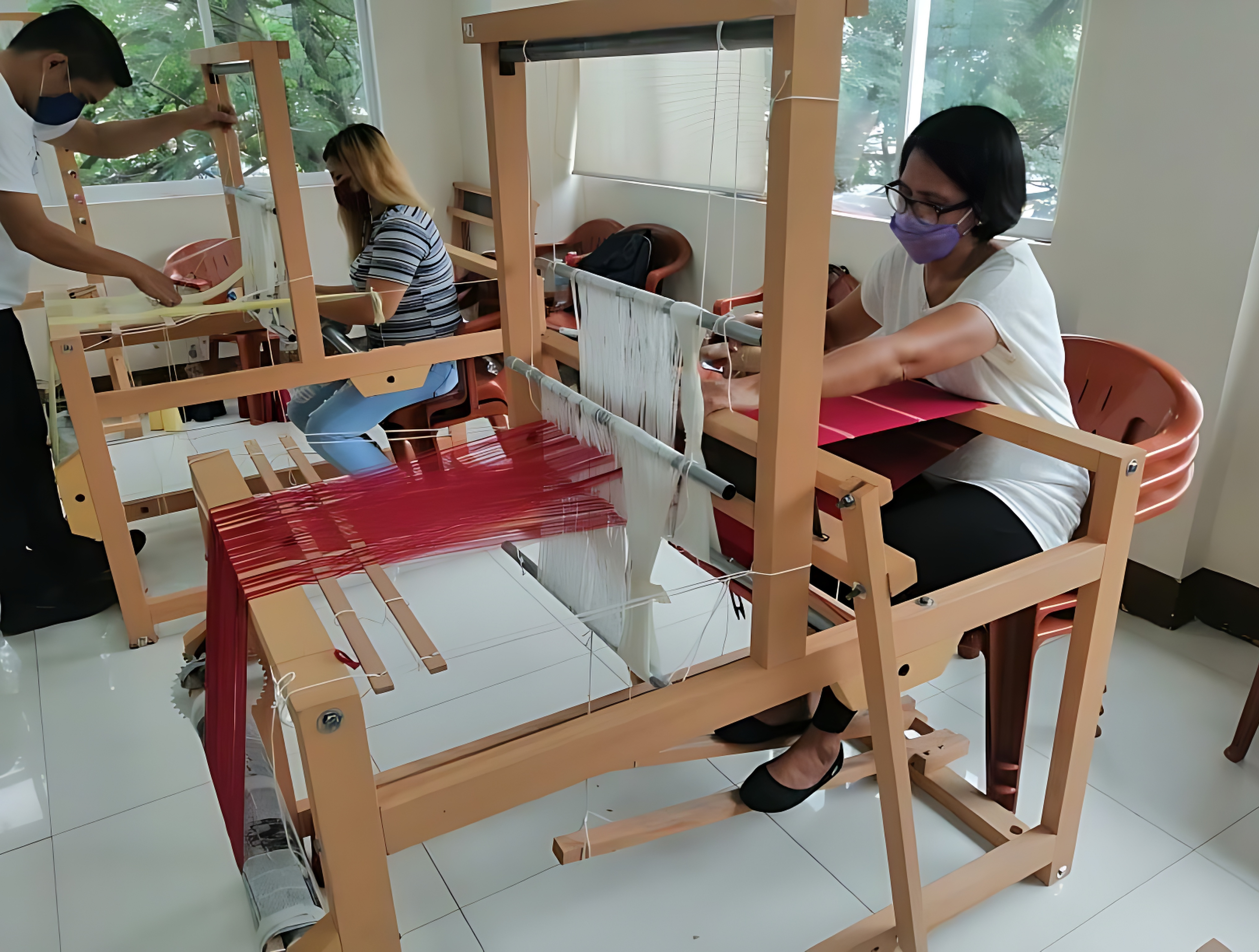 HARVEST creative community hub in Pasig City; Weavers engaged in the "Weaving in the City", sustainable livelihood program by Bayo: Standing-Randy Pontod, Dianne Amate-stripes shirt, Myra Gabriel- white shirt. This photo was taken during the early phase of the program, right after their training on Basic Handloom Weaving in October 2021.