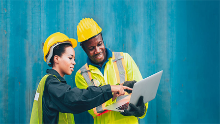 female & male construction workers reading laptop