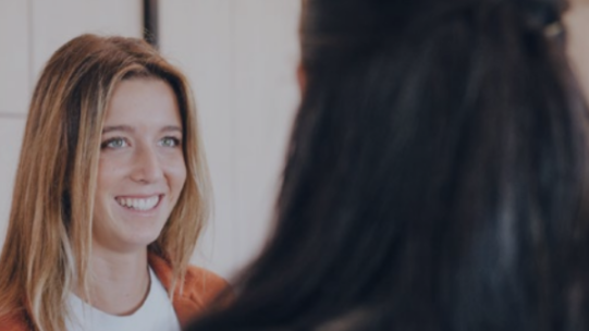 one woman smiling at another woman